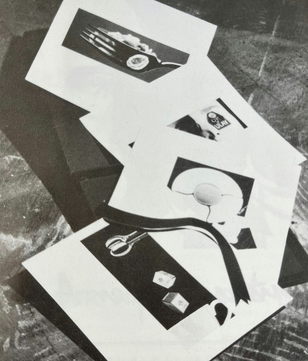 Image depicts a black and white photograph of a black box open to show glossy product sheets.